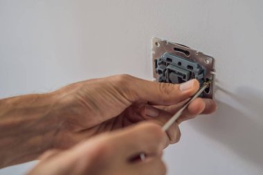 Usta elektrikçi eve bir soket takıyor.