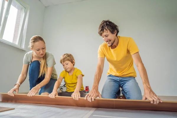 Famiglia felice l'installazione di nuovi pavimenti in laminato di legno su un pavimento caldo pellicola. Sistema di riscaldamento a pavimento a infrarossi sotto pavimento in laminato — Foto Stock