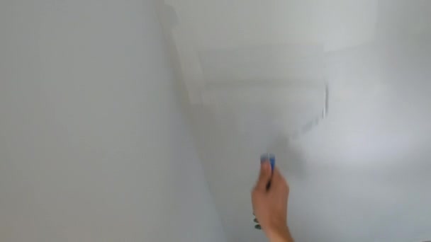 Point de vue. Un homme peint un mur avec un rouleau de peinture — Video