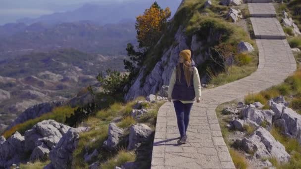 A young woman traveler visits the view point on the top of the Lovcen mountain. The Mausoleum of Petar II Petrovic-Njegos — Vídeo de Stock