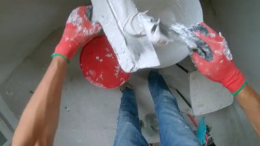 Pov atışı. Usta bir ressam duvara sıva yapıyor.