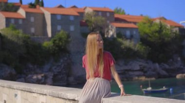 El kamerasıyla. Bir kadın gezgin Sveti Stefan adasını ziyaret ediyor. Budva şehrinin yakınlarında ünlü bir turistik mekan. Karadağ 'a Seyahat