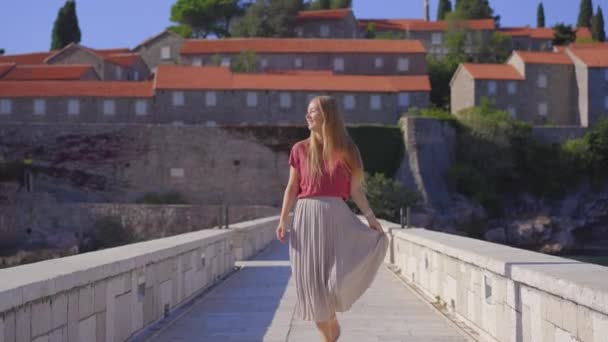 El kamerasıyla. Bir kadın gezgin Sveti Stefan adasını ziyaret ediyor. Budva şehrinin yakınlarında ünlü bir turistik mekan. Karadağ 'a Seyahat — Stok video