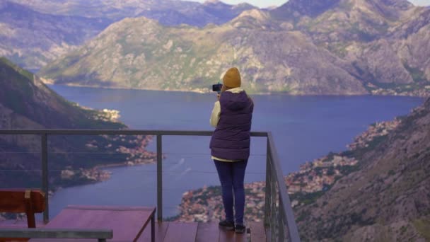 Een vrouw reist in het najaar in Montenegro. Ze kijkt naar de Boka Kotorska baai vanaf een uitkijkpunt op een berg — Stockvideo