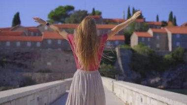 El kamerasıyla. Bir kadın gezgin Sveti Stefan adasını ziyaret ediyor. Budva şehrinin yakınlarında ünlü bir turistik mekan. Karadağ 'a Seyahat