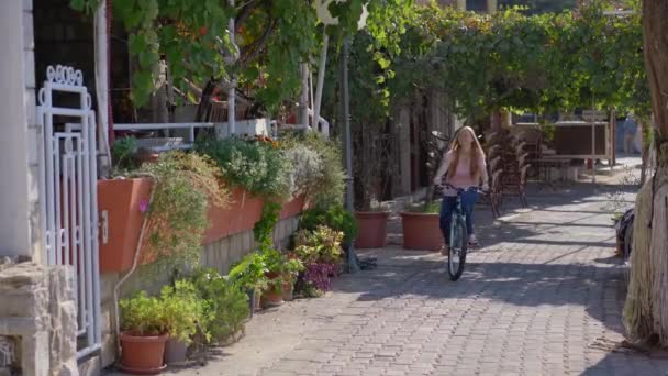 Una joven monta en bicicleta en la ciudad de Budva, un famoso lugar turístico en Montenegro. Viajes a Montenegro concepto — Vídeos de Stock