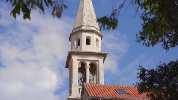 A church with a tall bell tower in the Old Town of Budva. The famous tourist spot in Montenegro — Vídeo de Stock