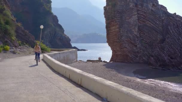 Mladá žena jezdí na kole ve městě Budva, slavném turistickém místě v Černé Hoře. Koncept cestování do Černé Hory — Stock video
