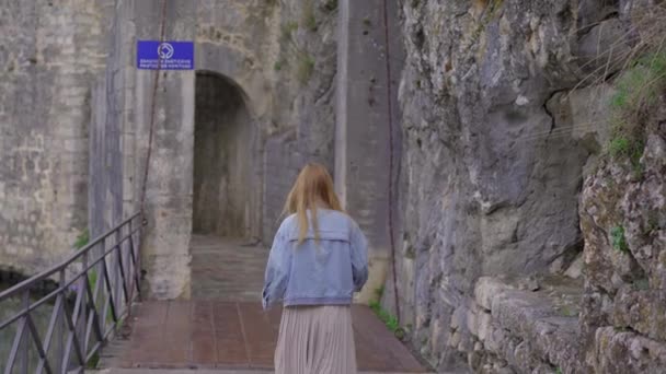 A young woman visits the Old town of Kotor in Montenegro. Travel to Montenegro concept. A world heritage site. Handheld shot — Vídeo de Stock