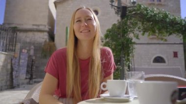 Karadağ 'ın Eski Budva kentini ziyaret eden genç bir kadın görülüyor. Karadağ 'a seyahat. Kahve içiyor ve bir kafede bir arkadaşıyla sohbet ediyor.