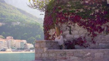 El kamerasıyla. Bir kadın gezgin Sveti Stefan adasını ziyaret ediyor. Budva şehrinin yakınlarında ünlü bir turistik mekan. Karadağ 'a Seyahat