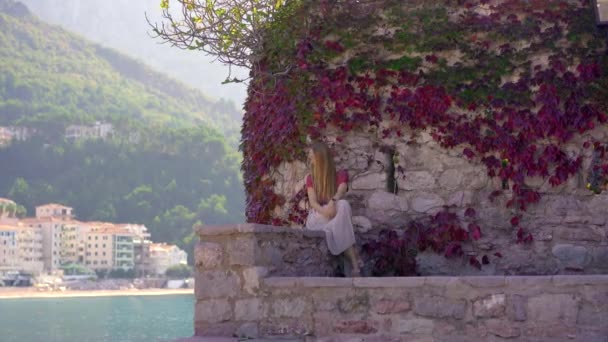 Σφηνάκι χειρός. Μια γυναίκα ταξιδιώτης επισκέπτεται το νησί Σβέτι Στέφαν. Διάσημη τουριστική τοποθεσία κοντά στην πόλη Μπούντβα. Ταξίδι στο Μαυροβούνιο — Αρχείο Βίντεο