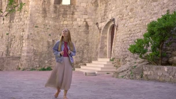 A young woman visits the Old town of Budva in Montenegro. Travel to Montenegro concept. A world heritage site — Vídeo de Stock