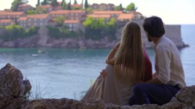 Bir erkek ve bir kadın gezgin Sveti Stefan adasını ziyaret ediyor. Budva şehrinin yakınlarında ünlü bir turistik mekan. Karadağ 'a Seyahat.