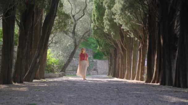 Eine junge Touristin spaziert durch das Tal im Park Milocer in der Nähe der Stadt Budva. Reisen nach Montenegro — Stockvideo