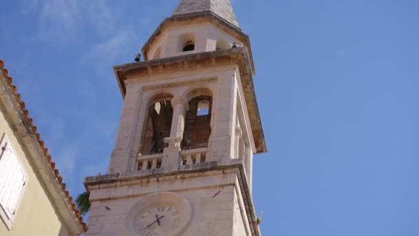 A church with a tall bell tower in the Old Town of Budva. The famous tourist spot in Montenegro — Vídeo de stock