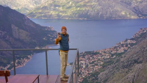A man travels in Montenegro in autumn. He looks at the Boka Kotorska bay from a view point on a mountain — Stok video