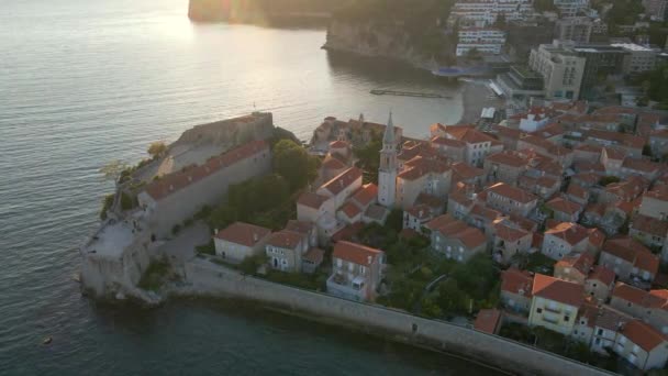 Vídeo aéreo. Disparo en cámara lenta. El casco antiguo de la ciudad de Budva popular destino turístico en Montenegro. Tiempo de puesta del sol. — Vídeo de stock