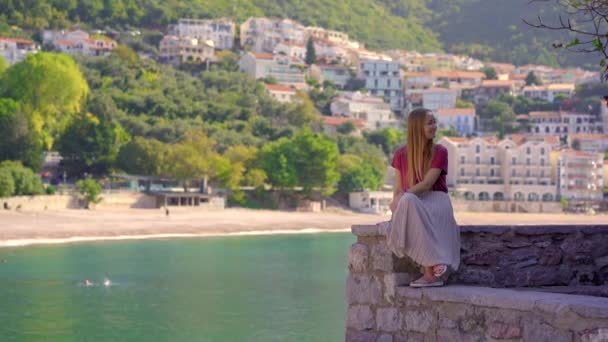 Handheld shot. A woman traveler visits the Sveti Stefan island. Famous tourist location near the city of Budva. Travel to Montenegro concept — стокове відео