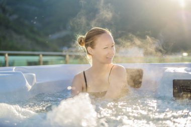 Genç kaygısız mutlu kadının portresi jakuzide rahatlayarak yeşil büyük dağların arka planında mutlu bir tatil hayatı yaşıyor.