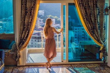Karadağ 'daki dağların ve kentin arka planında balkonda bir kadın var. Hayat terası oldukça mutlu bir yazlık ev. İlham şehri romantik oteli