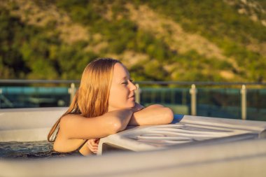 Genç kaygısız mutlu kadının portresi jakuzide rahatlayarak yeşil büyük dağların arka planında mutlu bir tatil hayatı yaşıyor.