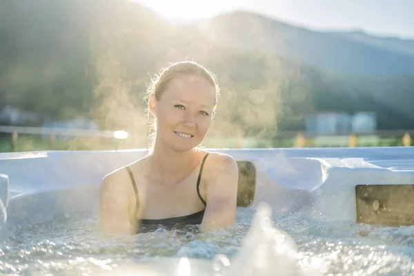 Portrait of young carefree happy smiling woman relaxing at hot tub during enjoying happy traveling moment vacation life against the background of green big mountains — Fotografia de Stock