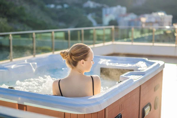 Retrato de la joven despreocupada feliz mujer sonriente relajarse en la bañera de hidromasaje durante el disfrute de la vida feliz viaje momento de vacaciones en el fondo de grandes montañas verdes — Foto de Stock