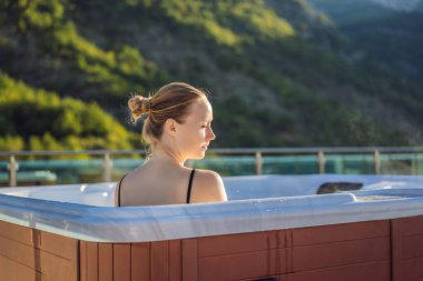 Genç kaygısız mutlu kadının portresi jakuzide rahatlayarak yeşil büyük dağların arka planında mutlu bir tatil hayatı yaşıyor.