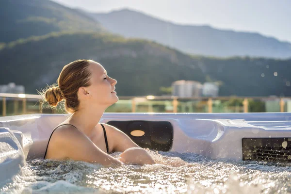 Portrait of young carefree happy smiling woman relaxing at hot tub during enjoying happy traveling moment vacation life against the background of green big mountains — Zdjęcie stockowe