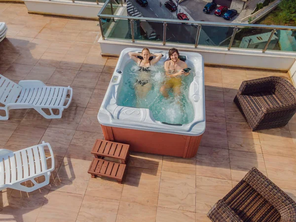 Drone zicht. Portret van jong zorgeloos gelukkig glimlachend paar ontspannen in hot tub tijdens het genieten van gelukkig reizen moment vakantie leven tegen de achtergrond van groene grote bergen — Stockfoto