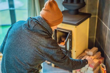 Man making fire in the fireplace. Rest in the mountains in Glamping. Cozy fireplace in a mountain house