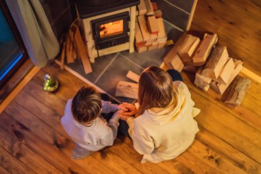 Anne ve oğlu Glamping 'de şöminenin başında vakit geçiriyorlar. Glamping 'deki dağlarda dinlen. Dağ evinde sıcacık şömine