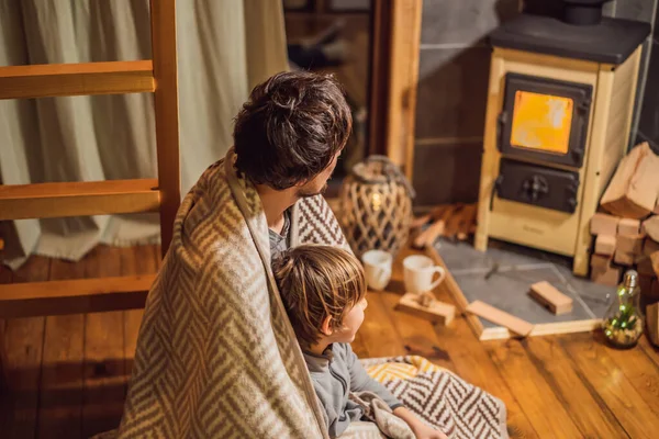Baba ve oğlu Glamping 'de şöminenin yanında vakit geçiriyorlar. Glamping 'deki dağlarda dinlen. Dağ evinde sıcacık şömine