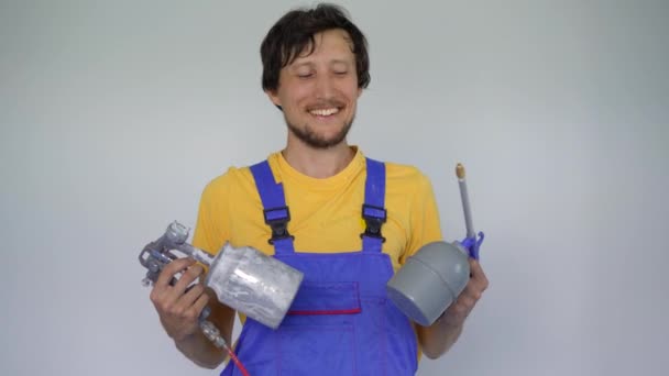En man professionell hem renoverare håller spraymålning enheter i sina armar. Han tittar på kameran leende — Stockvideo