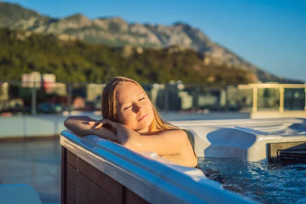 Portrait of young carefree happy smiling woman relaxing at hot tub during enjoying happy traveling moment vacation life against the background of green big mountains — Fotografia de Stock