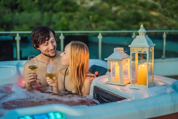 Retrato de joven despreocupada feliz pareja sonriente relajarse en la bañera de hidromasaje durante el disfrute de la vida feliz viaje momento de vacaciones en el fondo de grandes montañas verdes —  Fotos de Stock