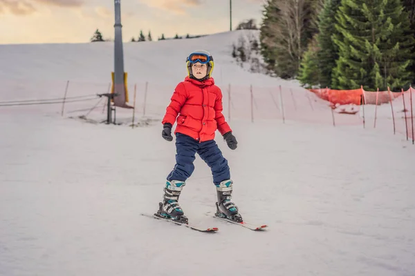 산악 지대에서의 어린이 스키. 안전 헬멧, 고글, 폴을 가진 활달 한아이. 스키는 어린 아이들을 위한 경주입니다. 가족을 위한 겨울 스포츠. 아이들은 알파인 학교에서 스키 레슨을 합니다. 눈 속의 좀 더 위험 한 경주 — 스톡 사진
