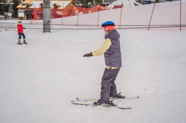 Kayak öğrenen bir kadın. Genç bir kadın dağlarda karlı bir yolda kayak yapıyor.