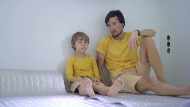 Батько син викладає і приклеює утеплювач для підлоги, на який потім кладуть ламінат — стокове відео