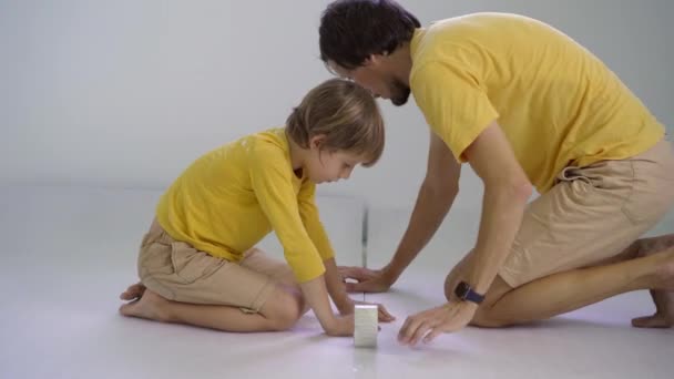 Otec a syn leží a lepí izolaci na podlahu, na kterou pak položí laminát — Stock video