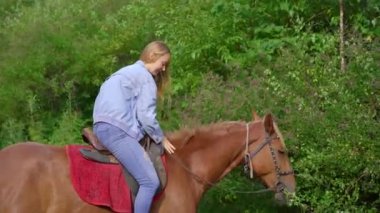 Ormanda at binen bir kadın. Atı bitkileri yiyor.