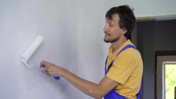 Um homem trabalhador da construção profissional pintar a parede usando um pintor de rolos — Vídeo de Stock