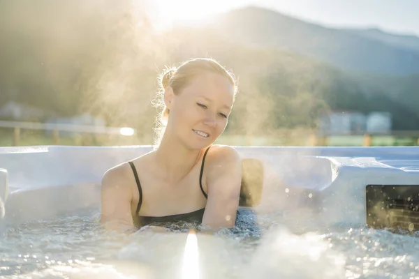 Portrait of young carefree happy smiling woman relaxing at hot tub during enjoying happy traveling moment vacation life against the background of green big mountains — Zdjęcie stockowe