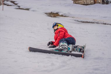 Çocuk dağlarda kayak yapıyor. Güvenlik kaskı, gözlüğü ve direkleri olan aktif bir çocuk. Küçük çocuklar için kayak yarışı. Aile için kış sporu. Alp okulunda çocuklar kayak dersi alıyor. Küçük kayakçı karda yarışıyor