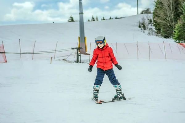 Kinderskifahren in den Bergen. Aktives Kleinkind mit Schutzhelm, Schutzbrille und Stöcken. Skirennen für kleine Kinder. Wintersport für die Familie. Kinder-Skikurs in der Alpinschule. Kleine Skifahrer rasen im Schnee — Stockfoto