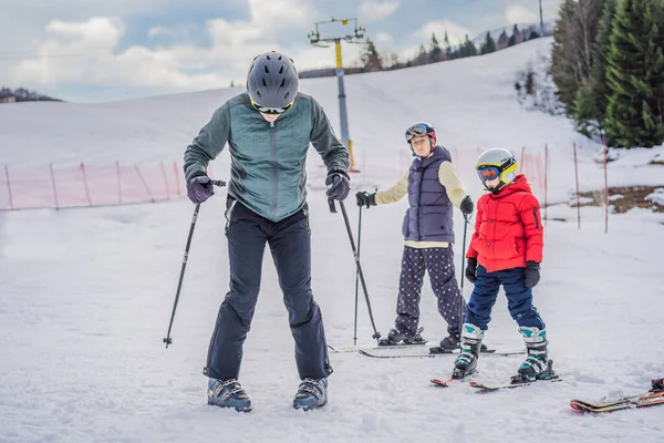 妈妈和儿子正在和老师一起学习滑雪.带着安全帽、护目镜和电线杆的活泼幼儿。滑雪比赛的幼儿。家庭冬季运动。高山学校的儿童滑雪课 — 图库照片