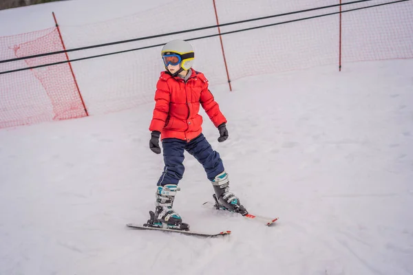 Ski d'enfant en montagne. Enfant tout-petit actif avec casque de sécurité, lunettes et bâtons. Course de ski pour jeunes enfants. Sport d'hiver pour la famille. Cours de ski pour enfants à l'école de ski alpin. Petit skieur de course dans la neige — Photo