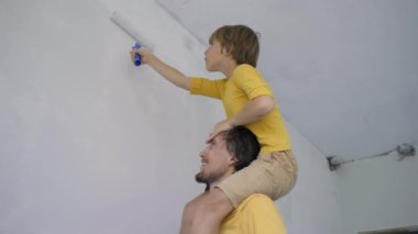Sarı tişört giyen bir baba ve oğul, duvarları tekerlekli boyayla boyarlar. Dairelerini yeniliyorlar. DIY ev yenileme konsepti. Aile zamanı.