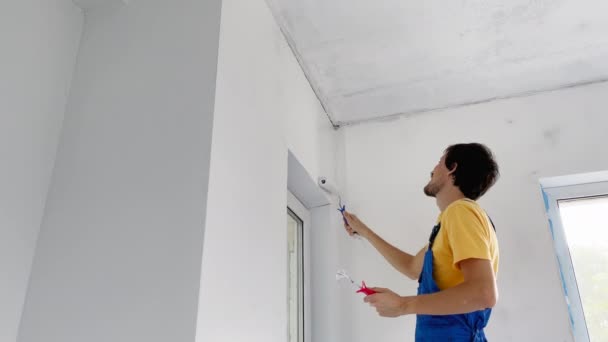 Un trabajador de la construcción profesional hombre pintar la pared con un pintor de rodillos. Disparo en cámara lenta — Vídeos de Stock